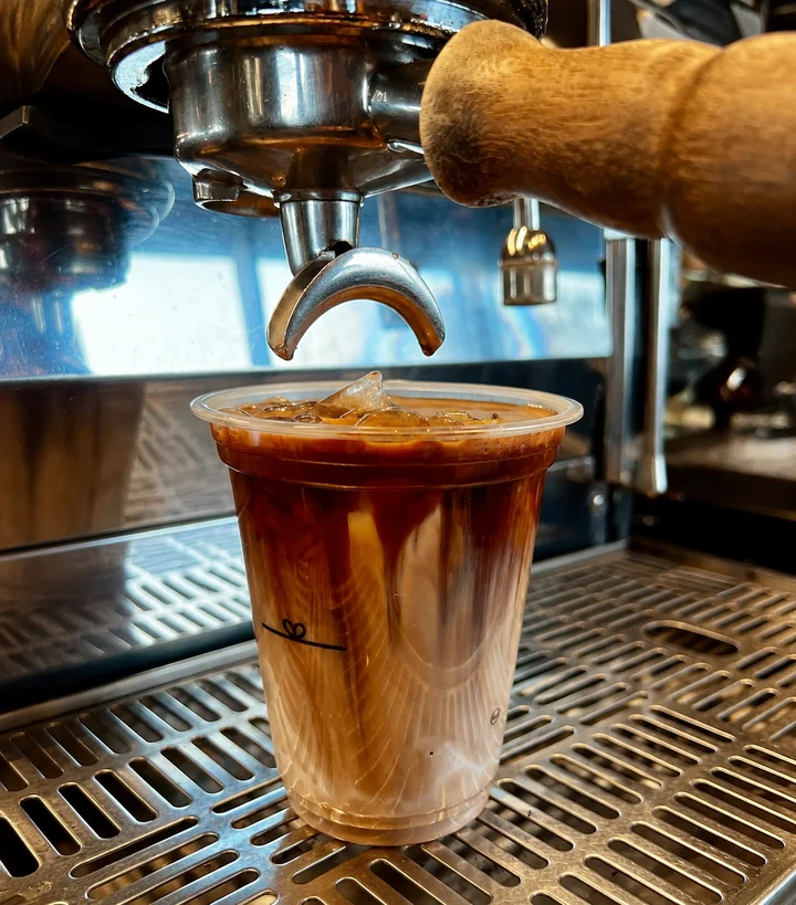 A glass of iced coffee beneath the espresso machine at Native
