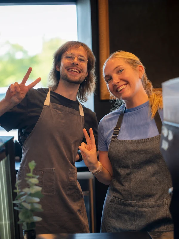 Two smiling people in aprons behind the Native Cafe counter