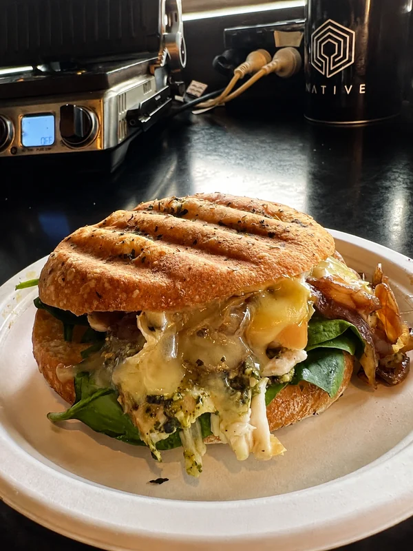 A toasted sandwich served beside a Native coffee cup